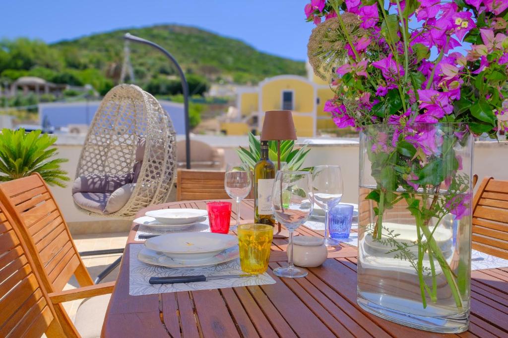 a wooden table with plates and glasses and flowers on it at La Casa di Barbara in Ponza