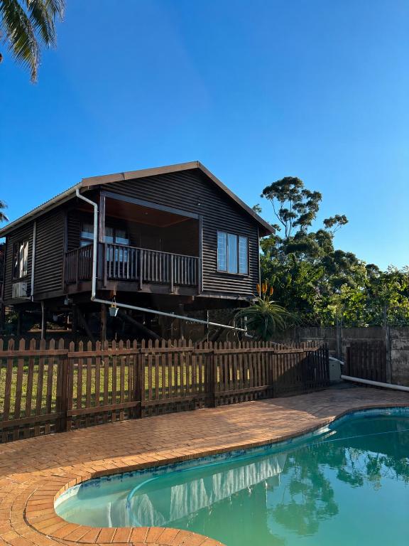 a house with a swimming pool in front of a fence at The Cottage Eplazini in Port Shepstone