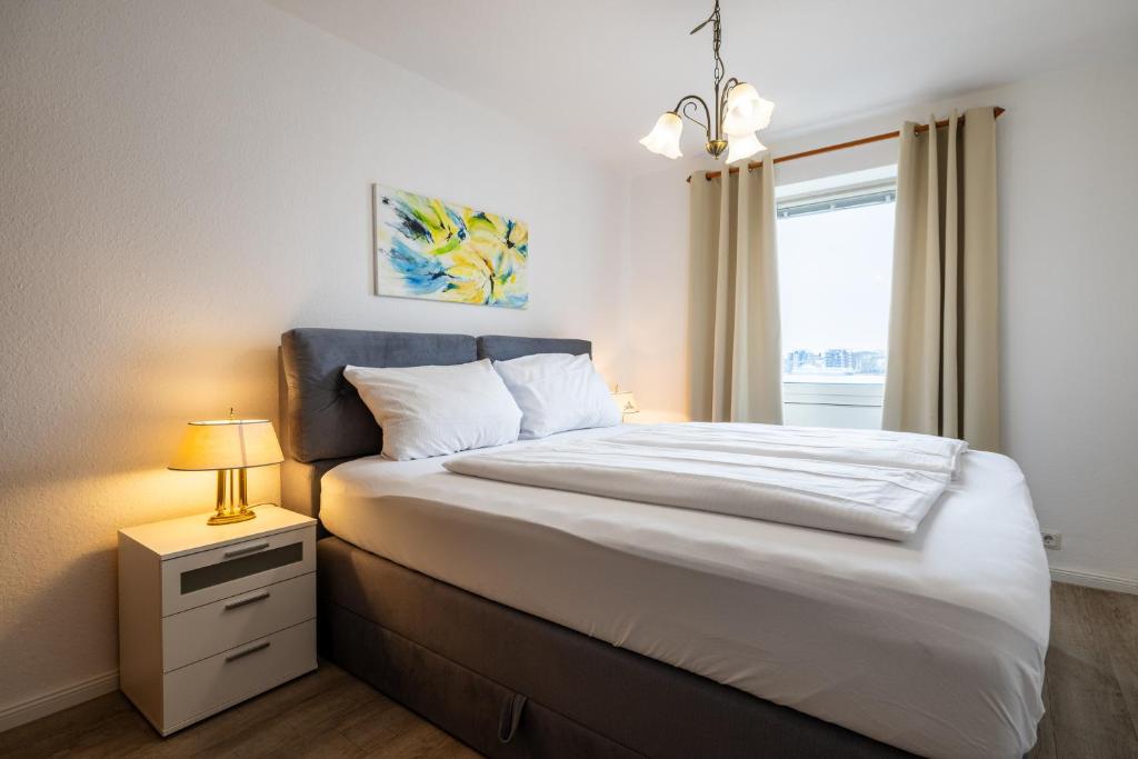 a bedroom with a bed with a lamp and a window at Exklusive Ferienwohnung am Südstrand mit Meerblick & Balkon Wohnung 10 in Wilhelmshaven