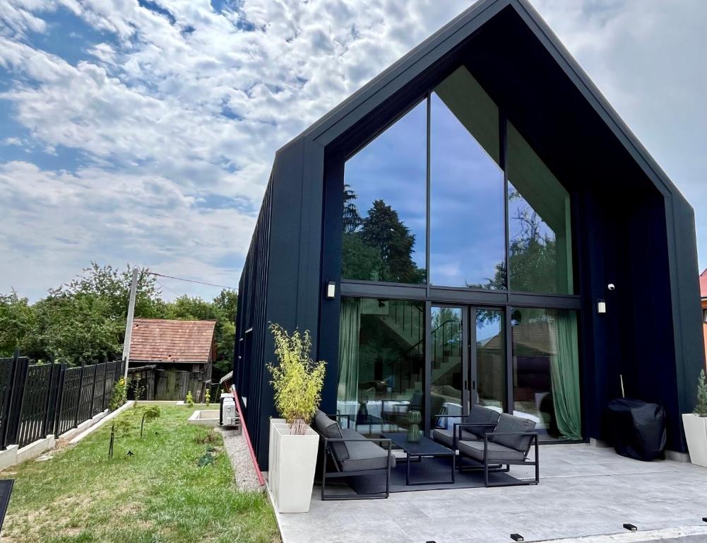 a black house with glass doors and chairs at Casa Verta in Skrad