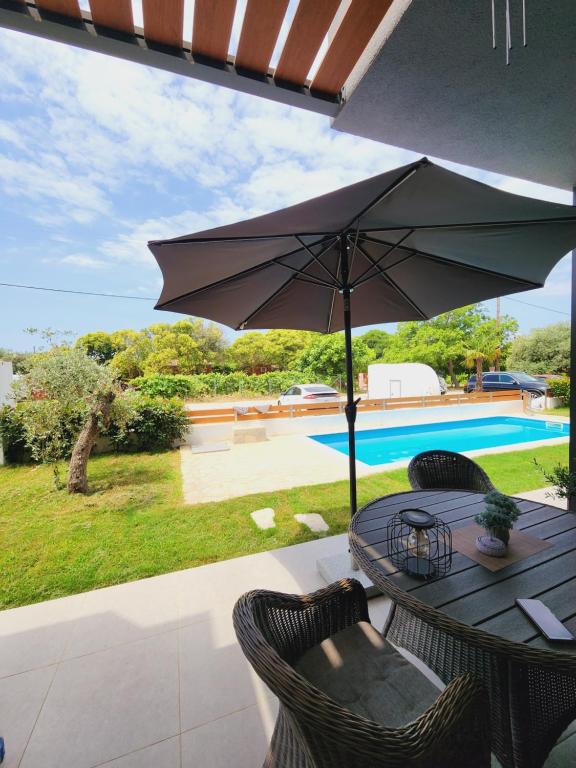 a table with an umbrella next to a pool at Sol Greco Apartment in Skala Rachoniou