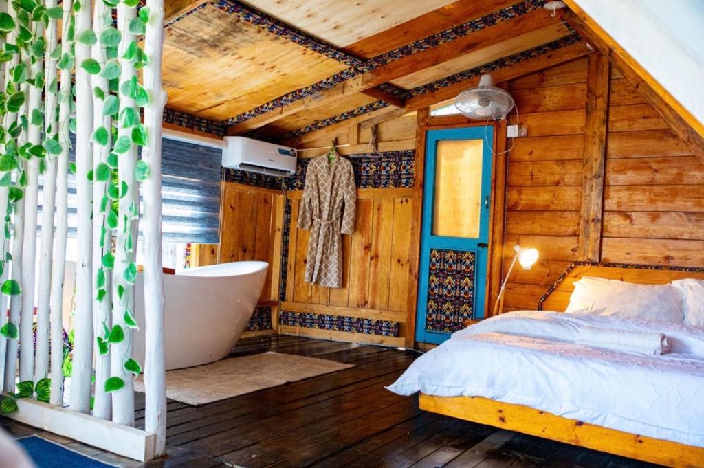 a bedroom with a bed and a bath tub in a room at Santorini by Busybee Lake Cabins in Mwanza