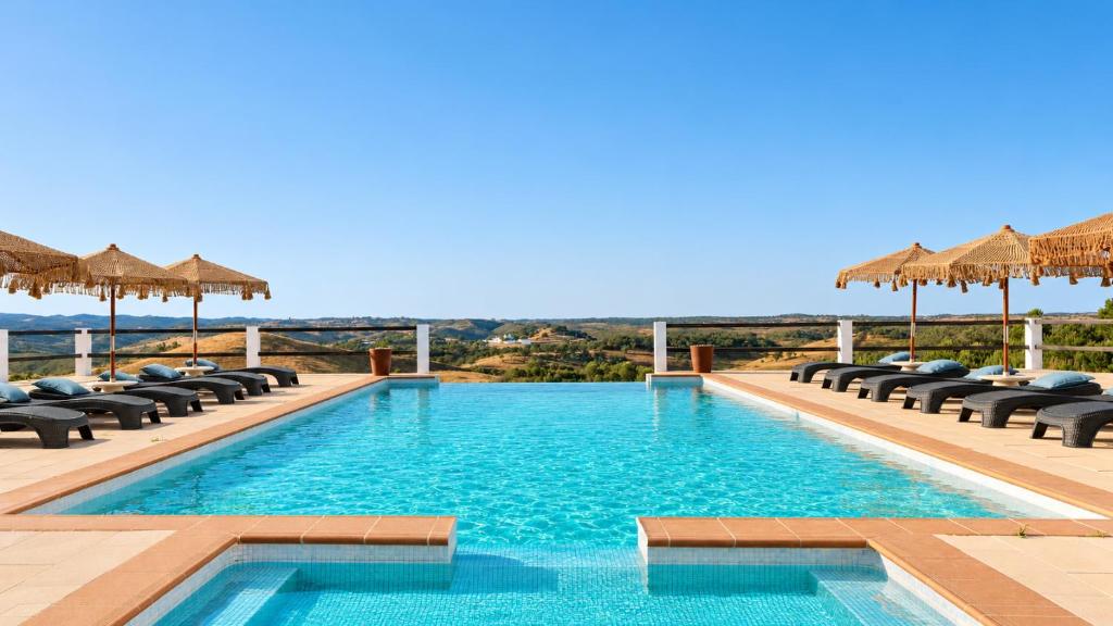 ein Schwimmbad mit Liegestühlen und Sonnenschirmen in der Unterkunft Monte do Alento - Castro da Cola in Alcaria