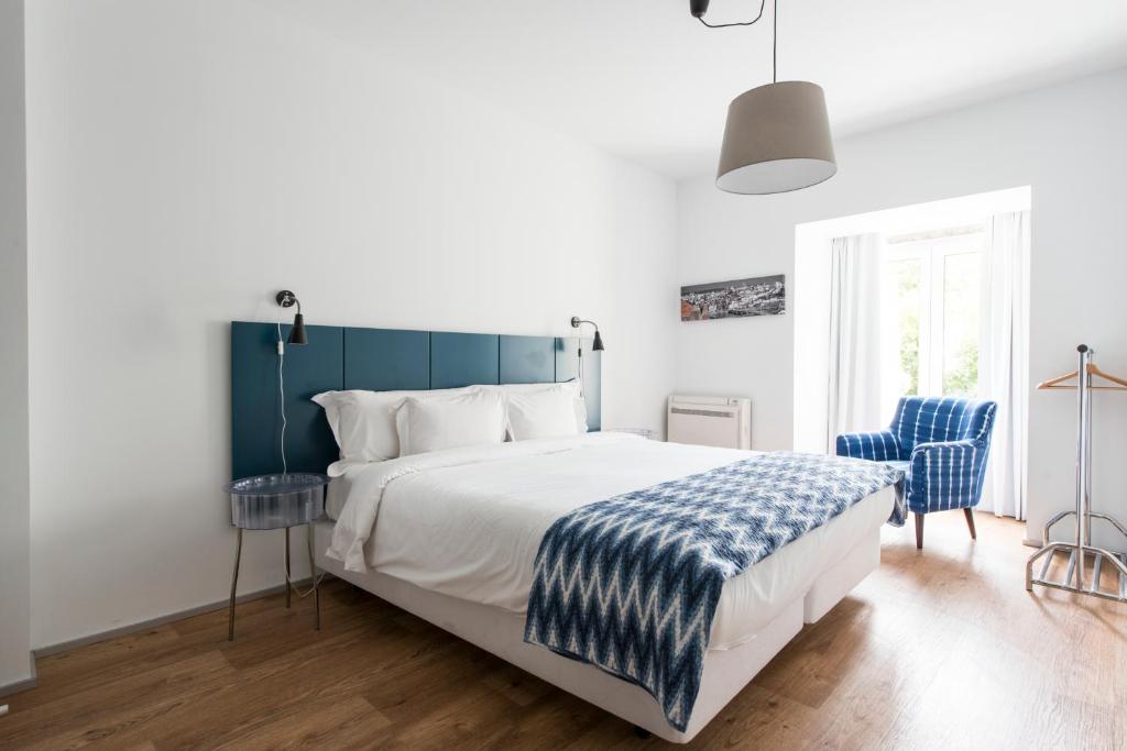 a bedroom with a large bed and two blue chairs at Alfama - Lisbon Lounge Suites in Lisbon