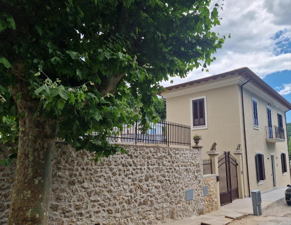 a white house with a stone wall and a tree at Villa Casinelli B&B in Isola del Liri