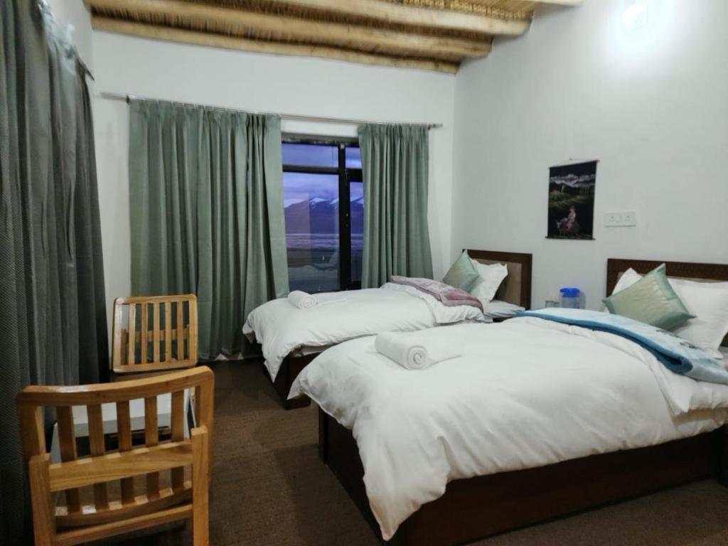 a bedroom with three beds and a window at Zim Retreat Tsokar in Pongunagu