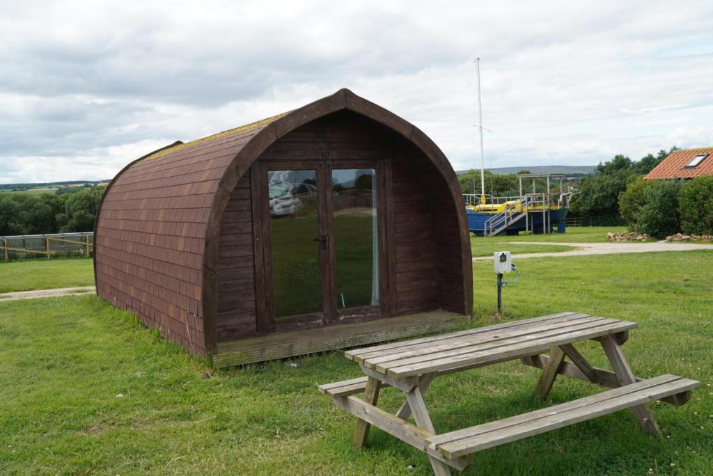 a wooden tent with a bench and a table at Broomfields Glamping Pods in Whitby