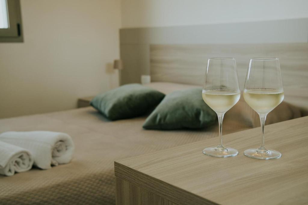 two glasses of white wine sitting on top of a bed at Nonno Turiddru Guest House in Marsala