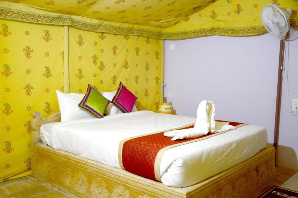 a bedroom with a bed in a yellow room at Musafir Desert Camp Jaisalmer in Jaisalmer
