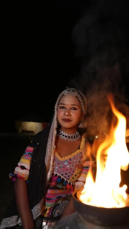 a woman sitting next to a pot of fire at Rumis Desert Camp in Jaisalmer