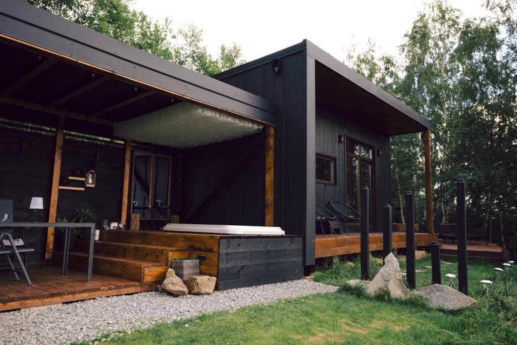 a black house with a porch and a deck at Nordik Crest in Mărişel