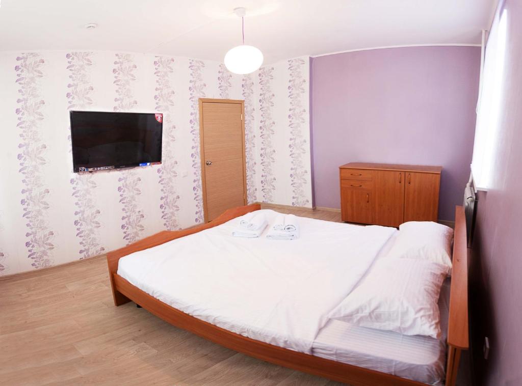 a bedroom with a bed and a flat screen tv at 2k Apartment near Ashan in Tyumen