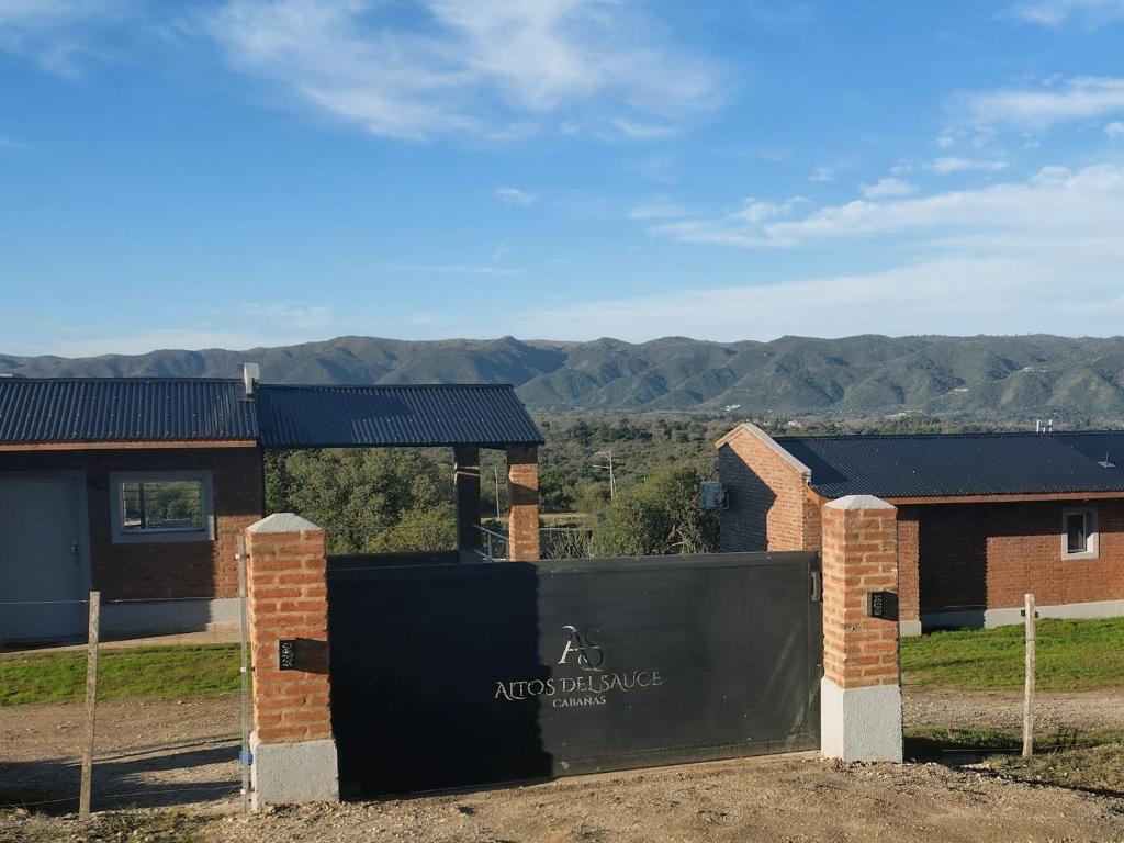 a sign in front of a building with mountains in the background at Cabañas Altos del Sauce in Villa General Belgrano