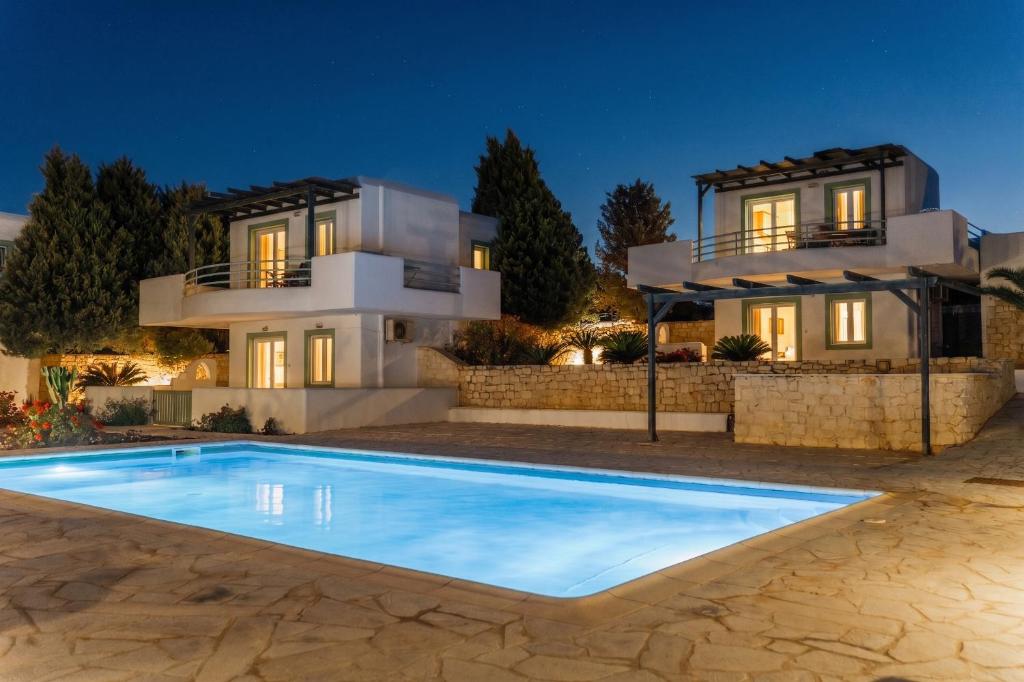 a villa with a swimming pool in front of a house at Cavo Plako Villas in Palekastron