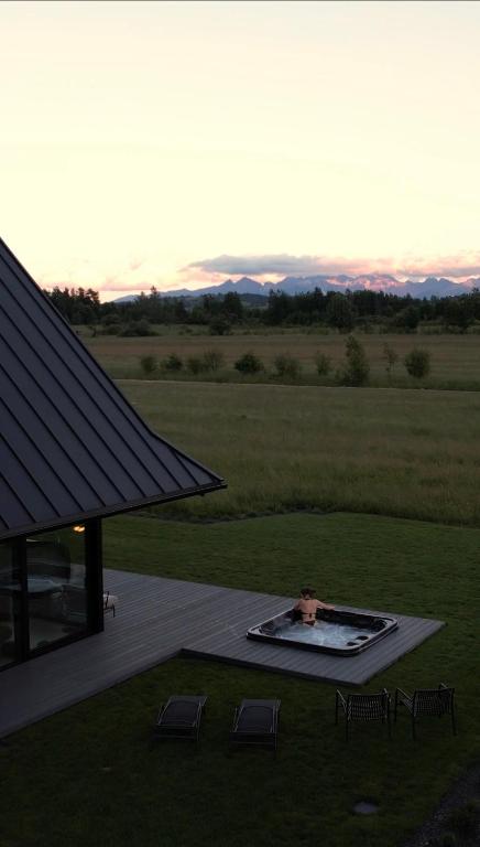 a person in a pool on a deck with chairs at Baniska Houses Mountain View DOM Z WIDOKIEM NA TATRY JACUZZI ORAZ SAUNA W CENIE in Szaflary