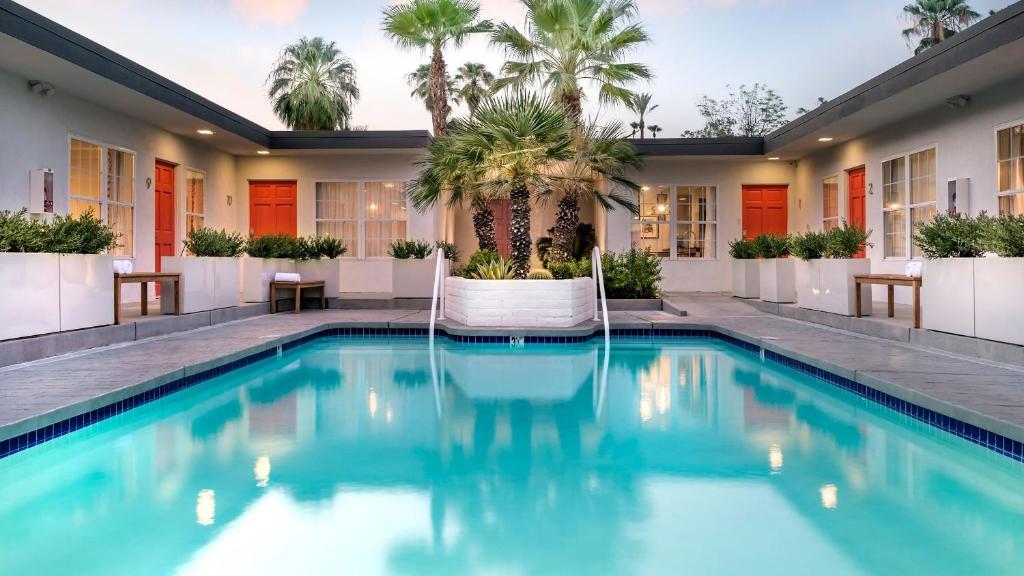 a swimming pool with palm trees in a building at The Weekend by AvantSay in Palm Springs