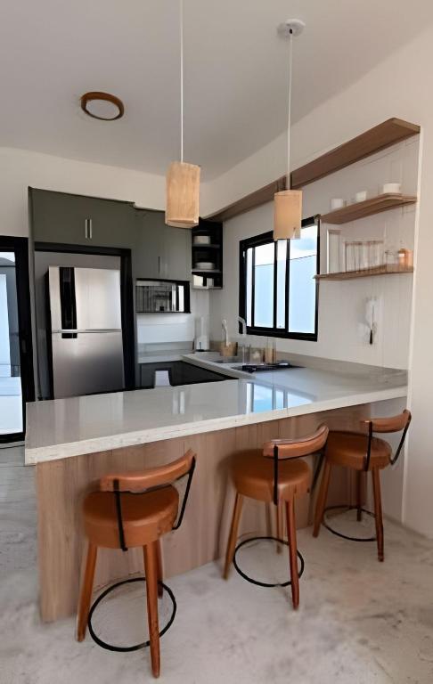 a kitchen with a large counter and two chairs at Wp White House- Estilo Grego 7 min do aqualinda in Andradina