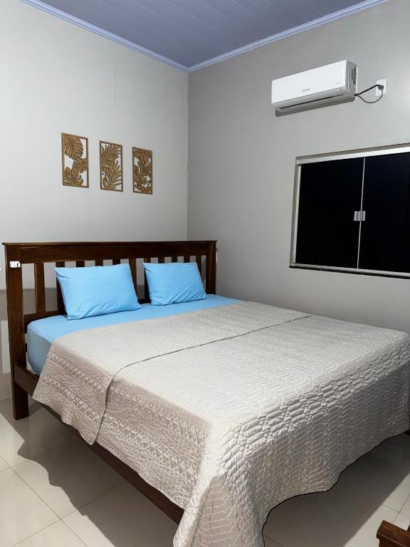 a bedroom with a bed with blue pillows and a television at Pousada Recanto dos Buritis in Manhã
