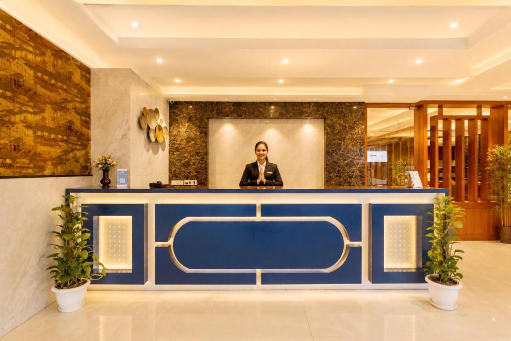 a woman standing behind a blue counter in a lobby at Hotel Corporate Plaza Near Terminal 3 Delhi International Airport With Free Airport Pickup in New Delhi