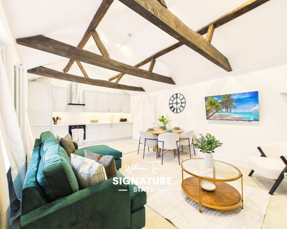a living room with a green couch and a table at NEW Artisan Apartment by Signature Stays - Modern - Spacious - Parking in Cheltenham