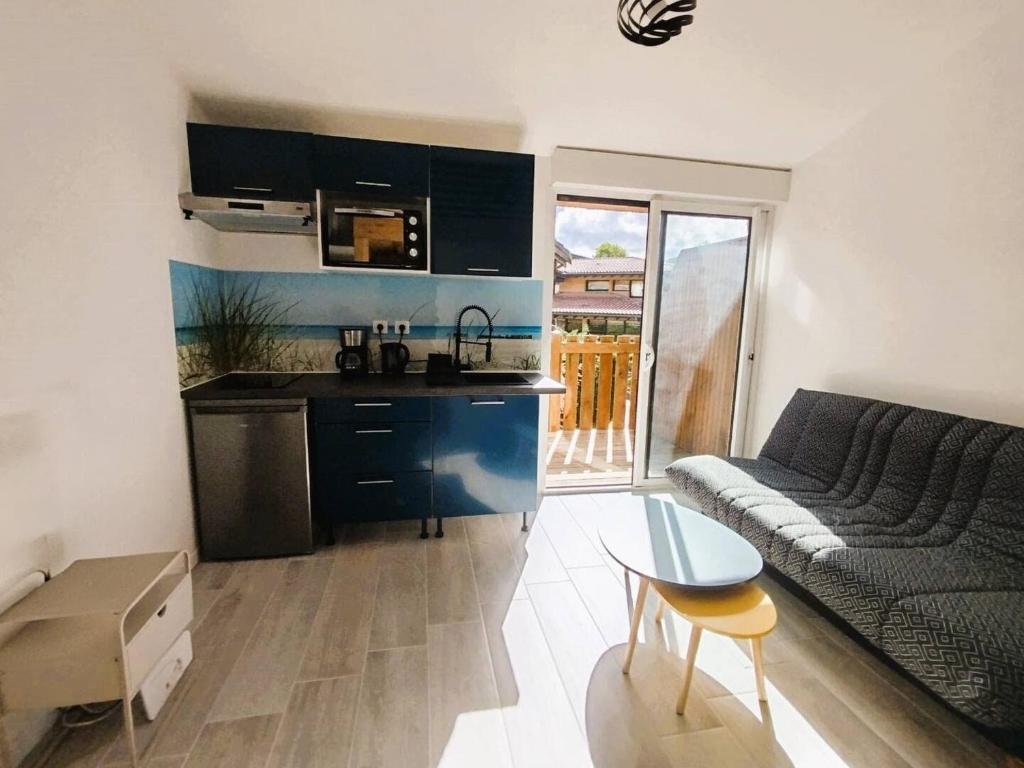 a kitchen and a living room with a couch and a table at Logement à deux pas du lac Carcans Maubuisson in Carcans