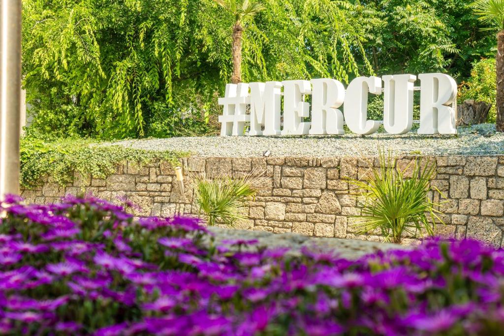 a sign for the entrance to a park with purple flowers at Hotel Mercur in Eforie Sud