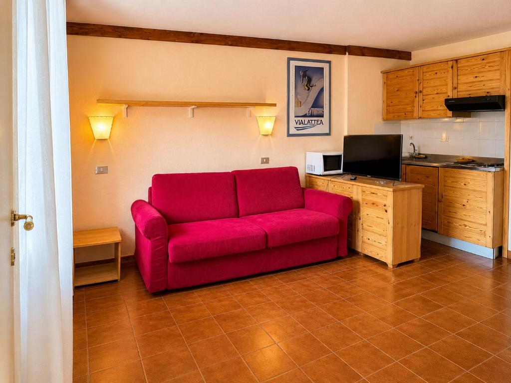 a red couch in a room with a kitchen at Hostdomus - A3-07 in Grange Sises