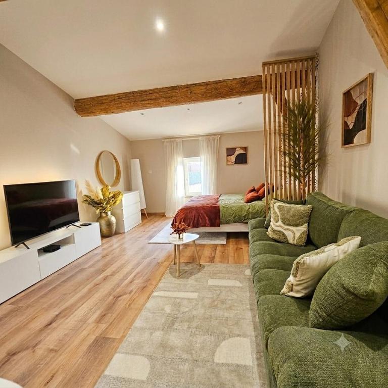 a living room with a green couch and a bed at Le 3Bis studio charmant proche Cap d'Agde in Bessan