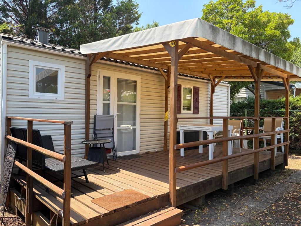 a wooden deck with a pergola on a house at Mobil-home proche plage in Saint-Julien-en-Born