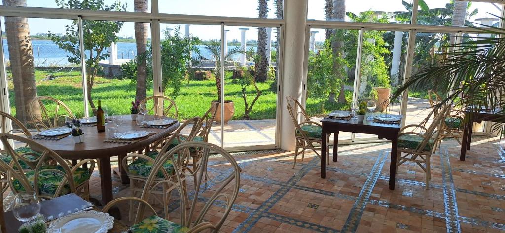 a dining room with tables and chairs and windows at Le Refuge in Larache
