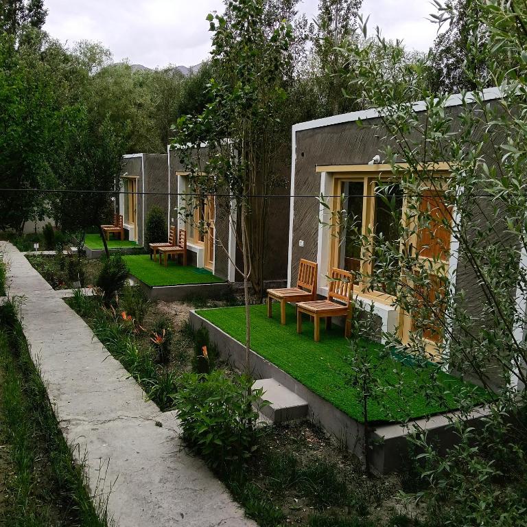 a small house with benches in a garden at Saser Camp in Nubra