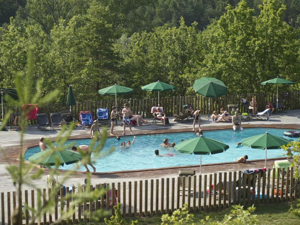 un gruppo di persone in una piscina con ombrelloni di Village Huttopia Sud Ardèche a Vagnas