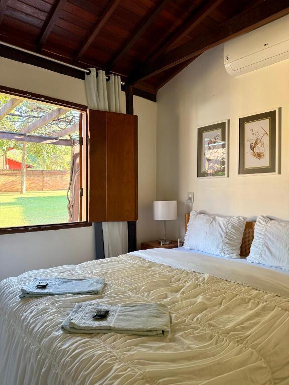 a bedroom with a large bed with a large window at Mini Casa-Aconchego e Fitness in Pirenópolis