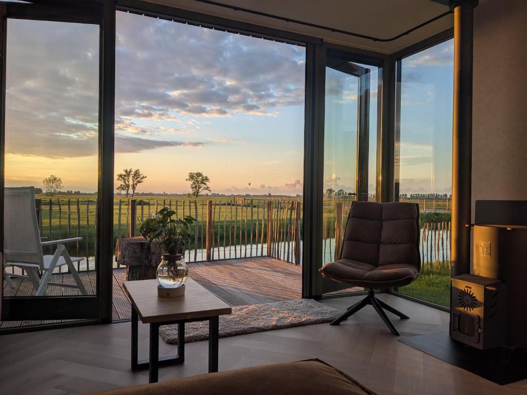 a living room with a chair and a large glass window at B&B Het Houten Huis in Brandwijk