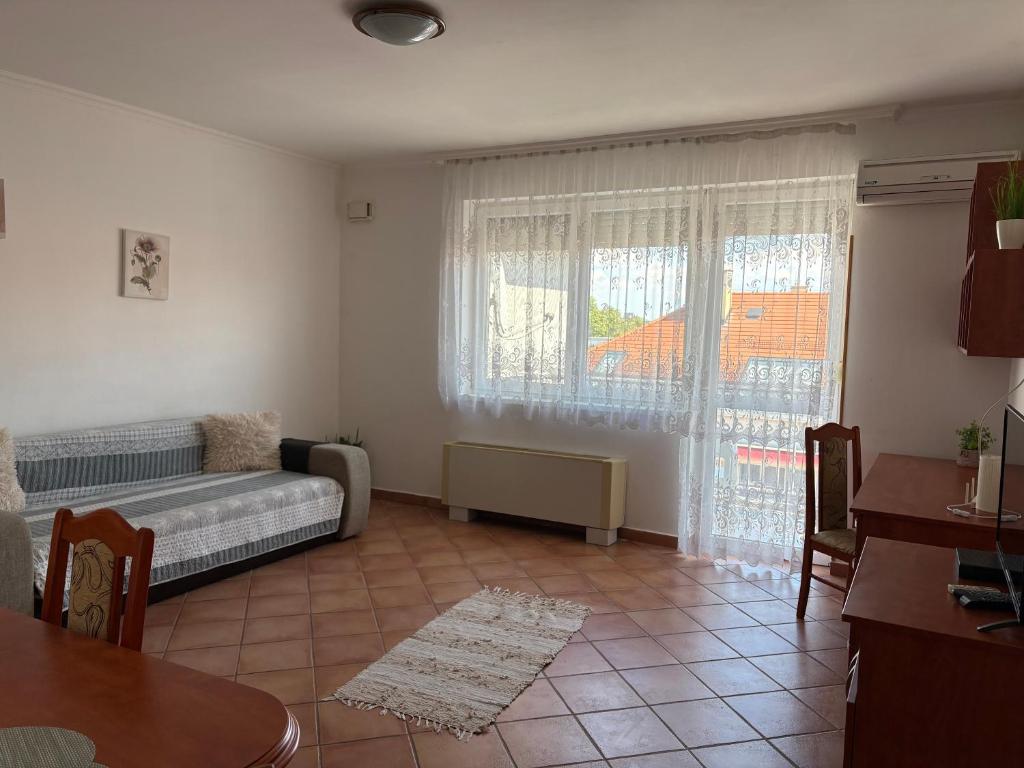 a living room with a bed and a window at Noemi Apartman in Hajdúszoboszló