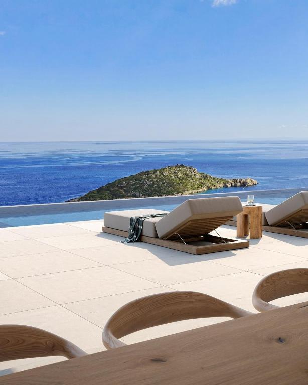 a patio with chairs and an island in the background at Gaia Place in Agios Nikolaos