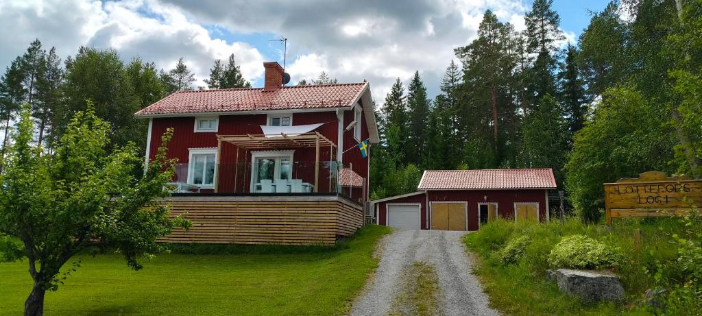 a red house with a porch next to a dirt road at Lottefors Logi in Bollnäs
