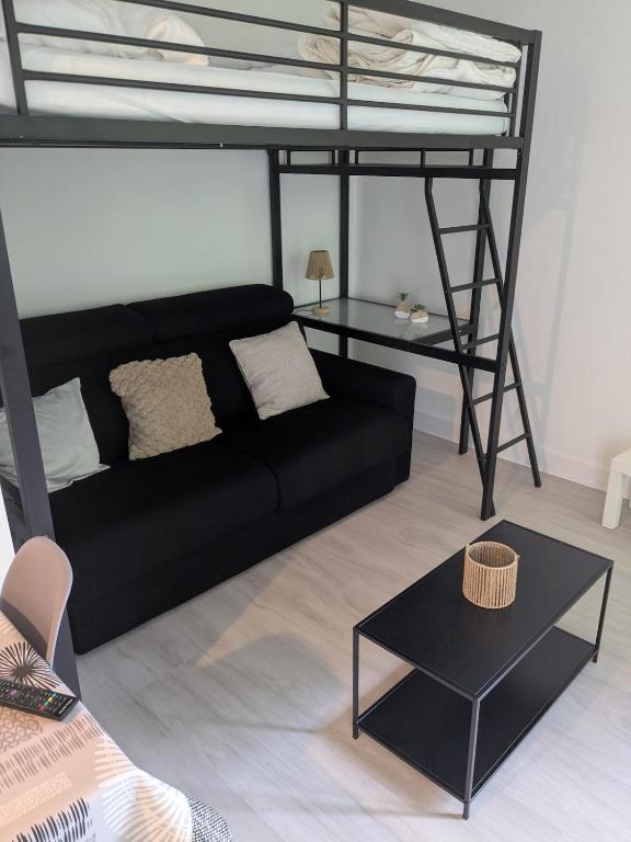 a living room with a black couch and a loft bed at Studio 4 personnes in Eaux-Bonnes