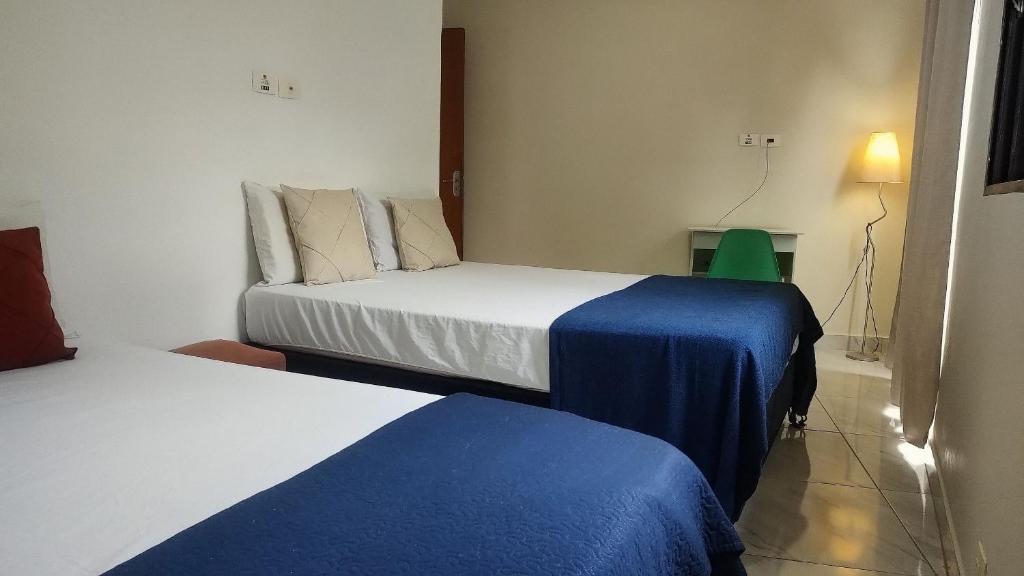a bedroom with two beds with blue and white sheets at Refúgio com Churrasqueira na Praia in Bertioga