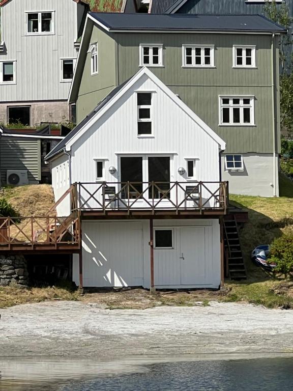 a large white house with a deck next to the water at Cottage by the waterfront in Vestmanna