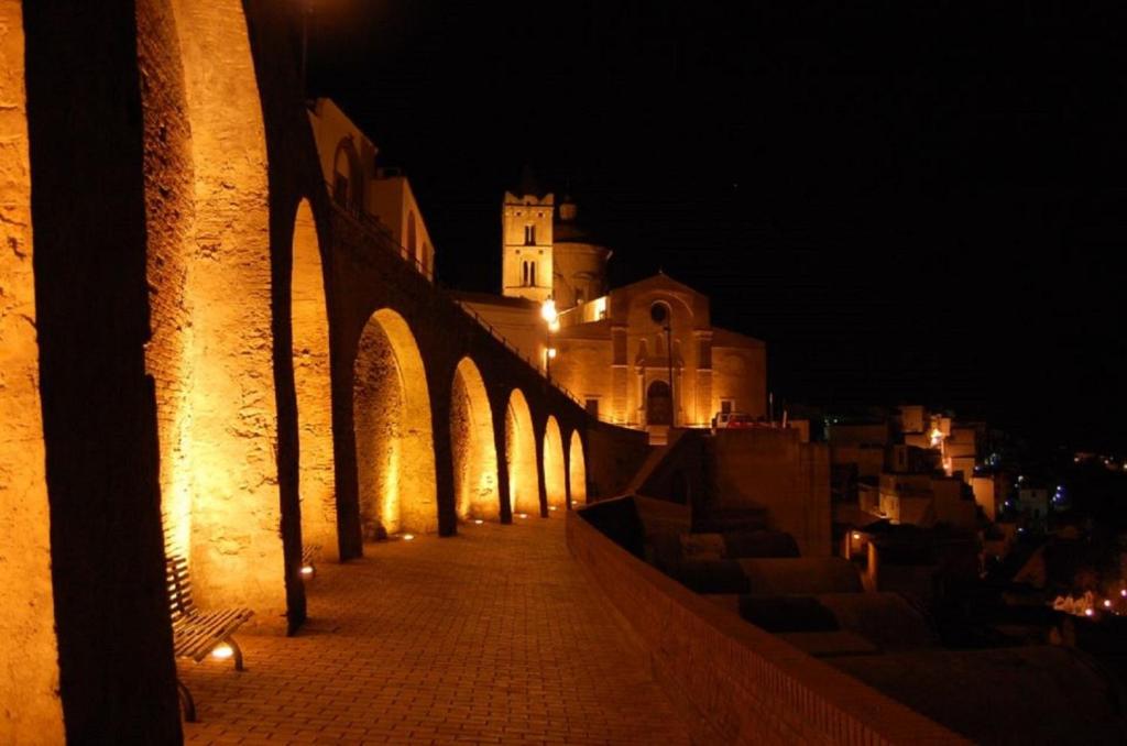 a building is lit up at night with a sidewalk at Nonna Rosa's Apartment in Pisticci