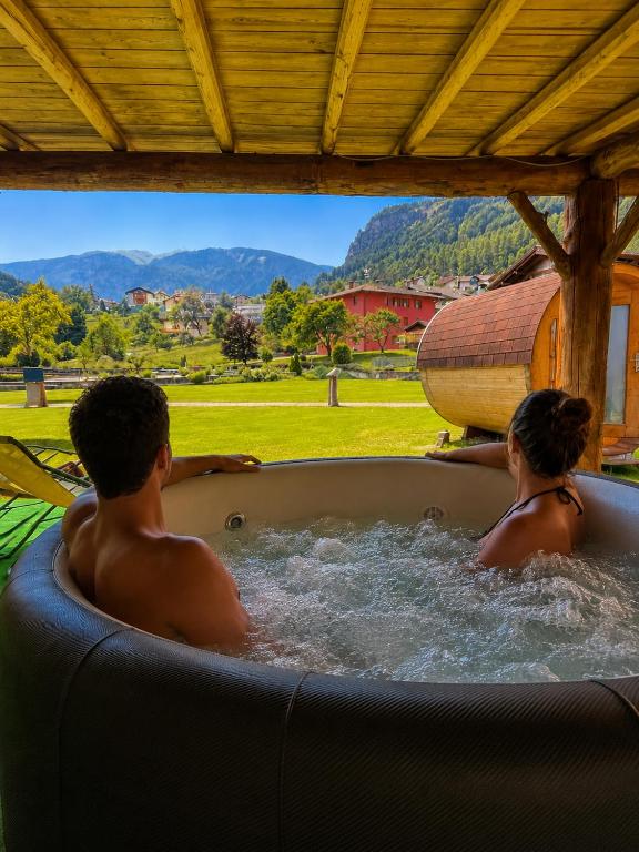 a man and a woman sitting in a hot tub at Hotel Garni Relax in Fai della Paganella