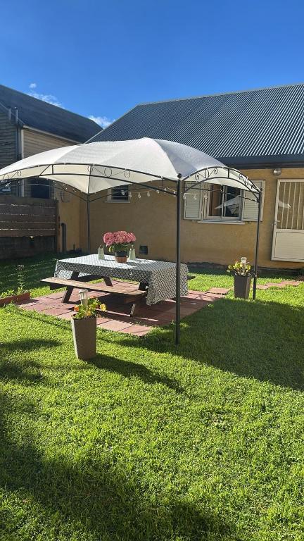 a picnic table under an umbrella in a yard at La Villa Nature in La Plaine des Cafres