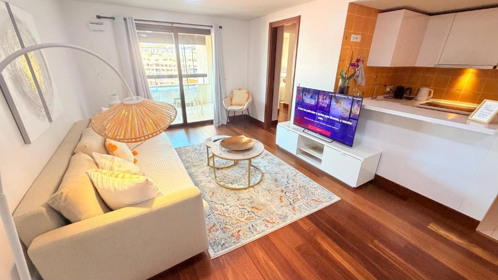 a living room with a couch and a tv at Seaside one bedroom apartment with terraces, garage & swimming pool in Cascais