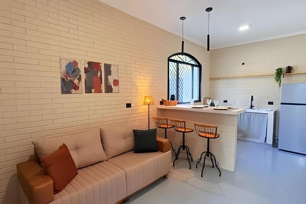a living room with a couch and a kitchen at 2 Suítes com Ar e Cozinha Completa in Andradina