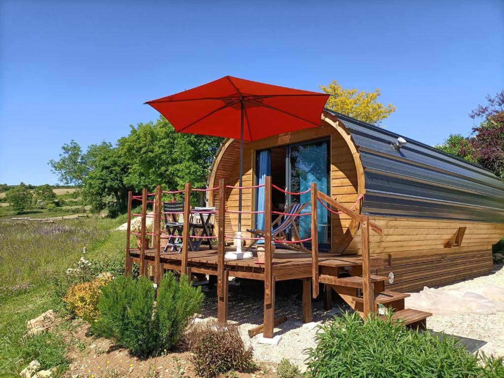 a wooden cabin with a deck with an umbrella at Tiny house chez Manou in Castelnau-de-Mandailles