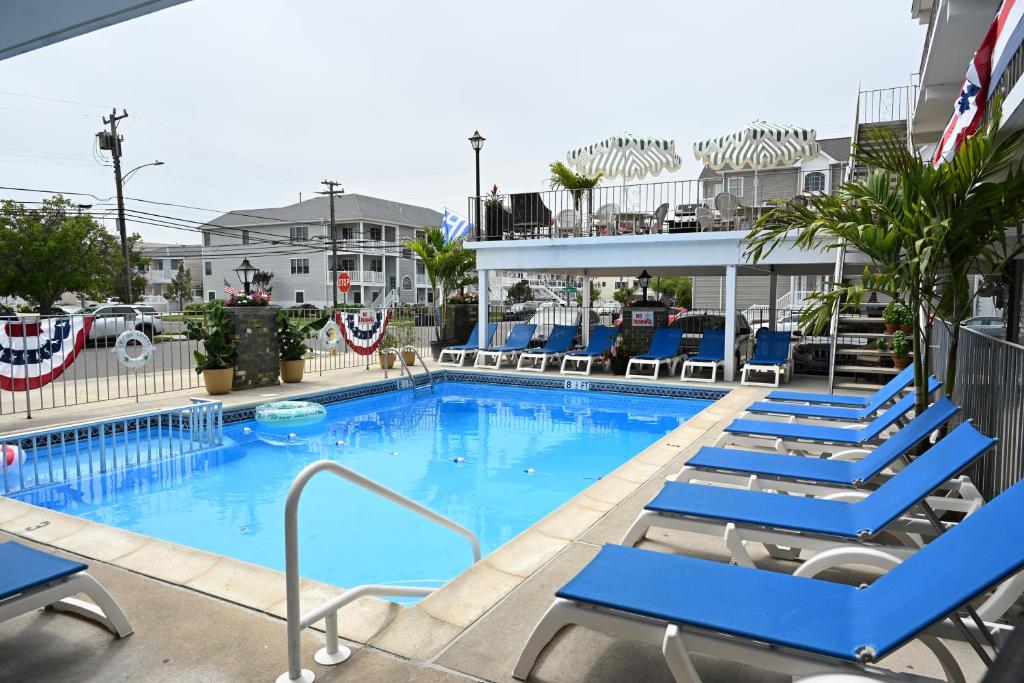 a pool at a hotel with blue lounge chairs at Grecian Garden Motel in North Wildwood