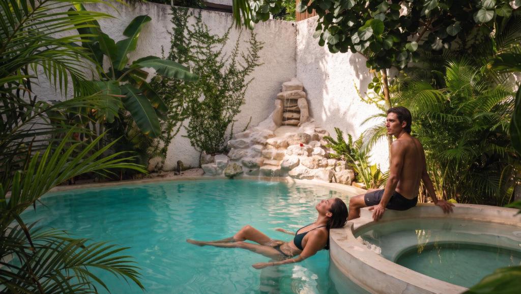 a man and a woman sitting in a swimming pool at Casa Wayra Tulum - Boutique Condos in Tulum