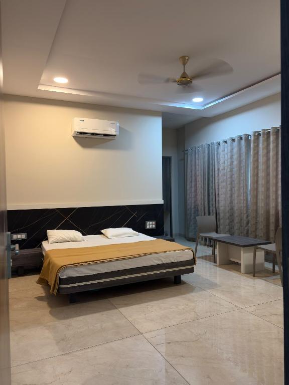 a bedroom with a bed and a table and a desk at Hotel VITHAI PALACE in Mehekar