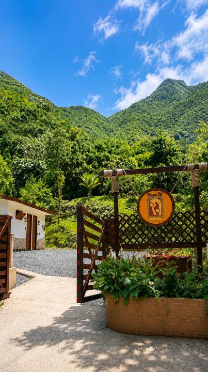 a gate with a sign on it with mountains in the background at Finca Ki' - Eco Farm Stay Bed & Breakfast - El Yunque Region in Naguabo
